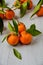 Three fresh tangerines with green leaves. Juicy mandarins orange and tangerine orange sliced on the gray wooden board. Citrus