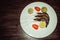 Three fresh uncooked shrimps with limes, tomatos on white plate. Wooden background. Raw prawns. Healthy delicious seafood dinner