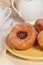 Three freshly baked brioche donuts on a yellow plate