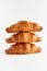 Three freshly baked croissants stacked on top of each other on a white background with copy space  vertical