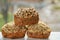Three freshly baked raisins cakes with sesame and sunflower seeds isolated on wooden table. Three muffins on blurred background