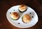 Three freshly cooked burgers on a white plate top view. Sesame bun, beef cutlet, spinach greens and flowing berry sauce