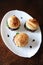 Three freshly cooked burgers on a white plate top view. Sesame bun, beef cutlet, spinach greens and flowing berry sauce