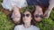 Three friendly girlfriends are lying on the grass with sunglasses and chewing gum.