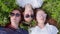 Three friendly girlfriends are lying on the grass with sunglasses and chewing gum.