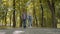 Three Friends With Backpacks Are Going to School. Mixed Racial Group of School Kids Walking in the Park holding hands