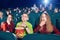 Three friends eating popcorn by watching movie.