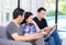 Three friends on line with multiple devices and talking sitting on a sofa