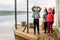 Three friends play fishing on wooden pier near pond. Two toddler boys and one girl at river bank. Children having fun doing grima