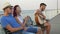 Three friends sitting on the bench with the sea as a background and singing with a guitar