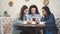 Three friends sitting in a cafe with a smart phone and having a funny conversation. Good girls with long beautiful black