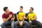 Three friends sitting on sofa wearing sports shirts smiling mocking interacting with each other holding trophy and ball