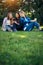 Three friends spend their free time sitting in the park on green lawn. Young pretty girls talking, smiling, looking photo