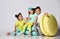 Three friends of triplets - two girls and a boy in bright clothes have fun at the birthday party  room decoration candy macarons