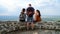 Three friendsone male and two females resting on the wall of the fortress,high viewpoint and valley