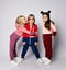 Three frolic kids bonde and brunette girls and blond boy in stylish sportswear are posing together hugging