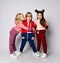 Three frolic kids bonde and brunette girls and blond boy in stylish sportswear are posing together hugging laughing