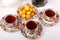 Three full porcelain teacups with floral pattern, box with tea, teapot and plate with wild apricots