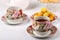 Three full porcelain teacups with floral pattern, teapot, biscuits and plate with wild apricots