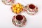 Three full porcelain teacups with hot tea and with floral pattern and plate with wild apricots
