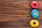 Three funny donuts on wooden background.