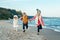 Three funny smiling laughing white Caucasian children kids friends playing running on ocean sea beach on sunset outdoors