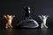 Three funny toy kittens with raised paws next to a wireless computer mouse. Dark background. A humorous concept about cats hunting