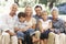 Three Generation Family Sitting On Sofa At Home