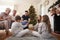 Three Generation Family Wearing Pajamas In Lounge At Home Opening Gifts On Christmas Day