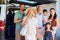 Three generation white family standing by car smiling to camera before leaving for vacation