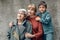 three generations grandmother great grandmother grandson are standing on street against a gray wall