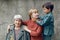 three generations grandmother great grandmother grandson are standing on street against a gray wall