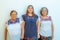 Three generations of latin Mexican women smiling, grandmother, granddaughter and daughter with floral printed blouses holding hand