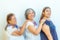 Three generations of smiling Mexican women in a row holding their shoulders