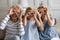 Three generations women with fingers making binoculars like eyeglasses shape