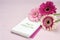 Three gerbera flowers lying on a writing pad, pastel pink colore