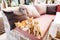 Three ginger cats on a pink sofa with multi-colored pillows in the room.