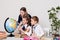 Three girls with books and a globe in geography class at the desk