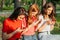 Three girls chatting with their smartphones at the park. Gen Z young girl friends using gadget and having fun outdoors