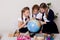 Three girls in the classroom studying geography globe of planet Earth