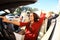 Three girls driving in a convertible car and having fun.