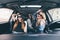 Three girls driving in a convertible car and having fun, listen music and dance