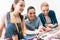 Three girls at garment factory. They are choosing pins for new dress.