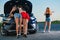 Three girls at road with broken car