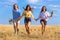 Three girls running on stubble field