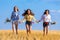 Three girls running on stubble field