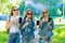 Three girls schoolgirl. Summer in nature. In hands holds phone. Gesture gesture is shown smartphone. In jeans clothes in