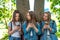 Three girls schoolgirl teen. In summer park by tree. He holds a smartphone in his hands, writes messages, reads