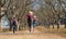 Three girls sisters running skipping down tree lined dirt road