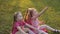 Three girls sitting on grass in park and laughing